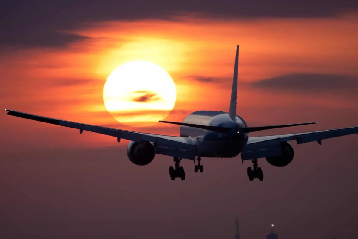 airplane flying toward the sunset or sunrise