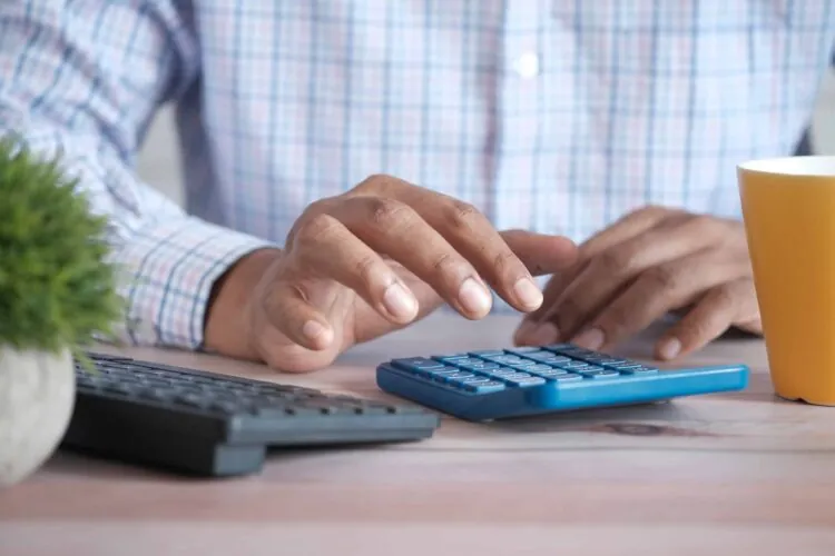 a person sitting at a desk using a calculator