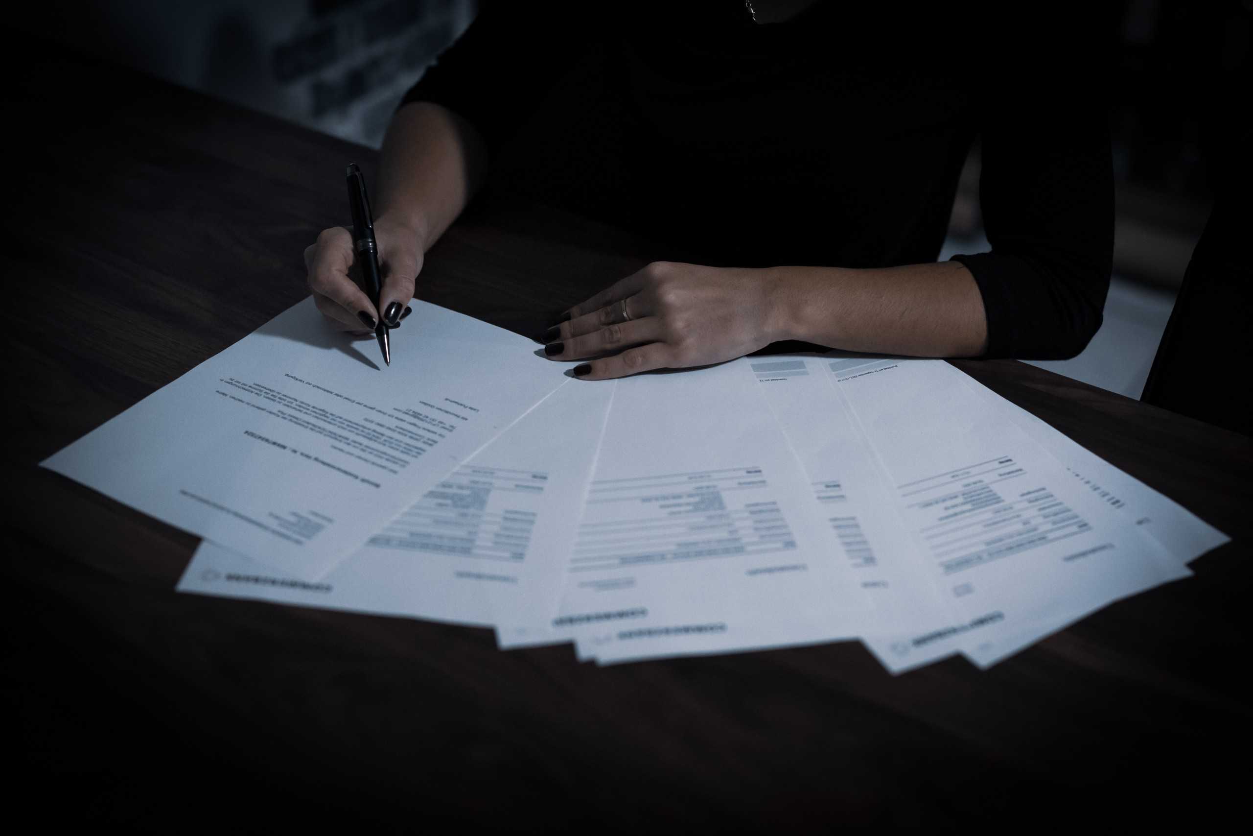 woman in workplace signing documents on a desk