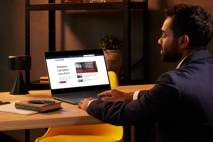 Businessman looks at mltaikins.com on laptop computer