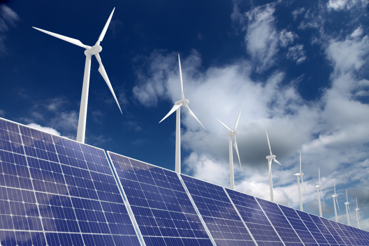 A upwards-pointing photo of solar panels and energy-generating windmills against a blue sky