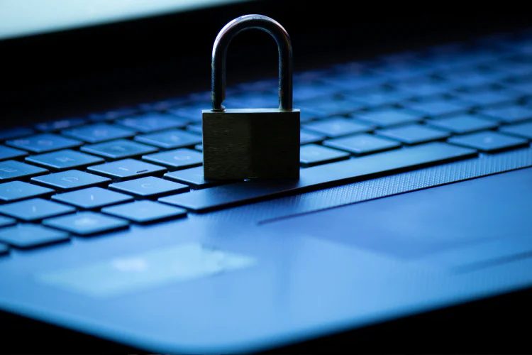 A closeup of a padlock sitting on a laptop keyboard in a dark room