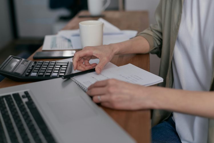 Business person doing paperwork, computer and calculator nearby