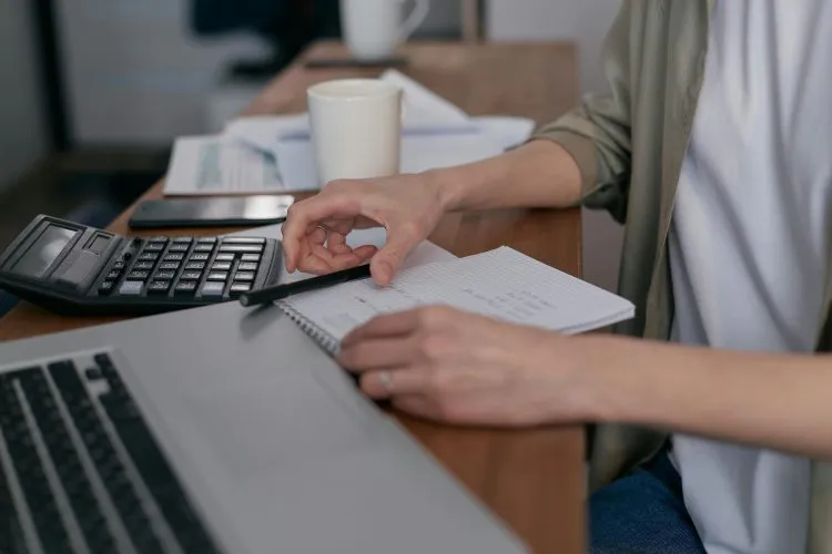 Business person doing paperwork, computer and calculator nearby