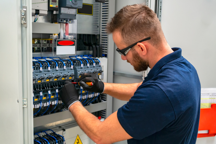 Worker performs maintenance on electrical panel