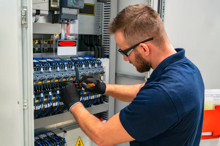 Worker performs maintenance on electrical panel