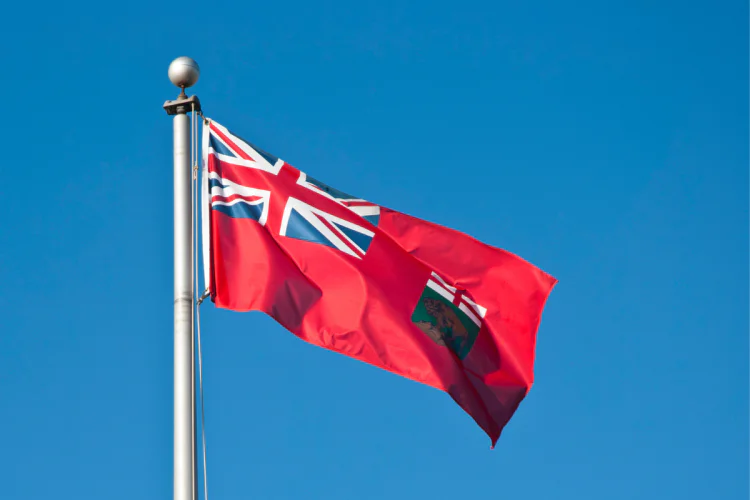 Manitoba flag flies against blue sky