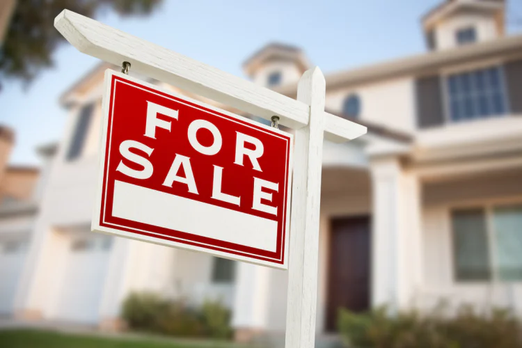 A photo of a for sale sign in front of a large, modern-looking home