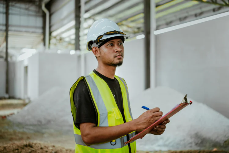 worker in hardhat and hi-vis vest holding clipboard