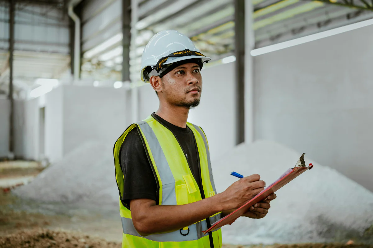 worker in hardhat and hi-vis vest holding clipboard