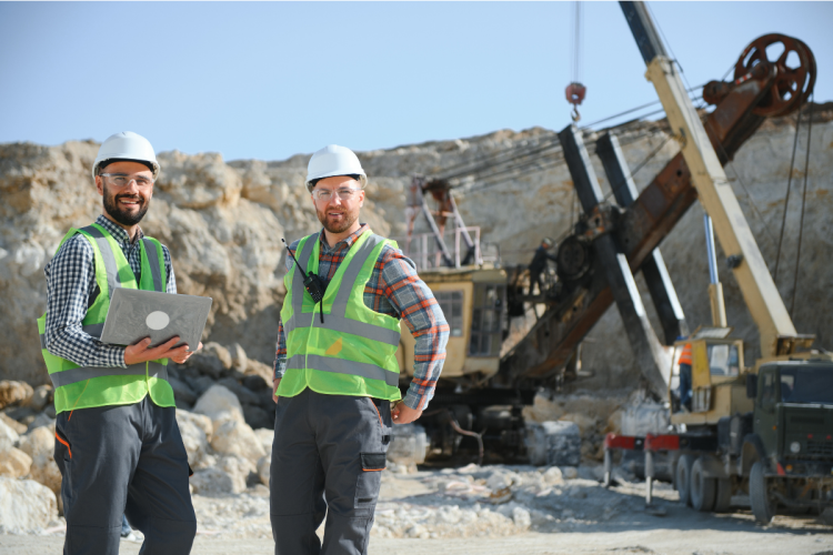 Two men in safety gear standing in front of mining equipment