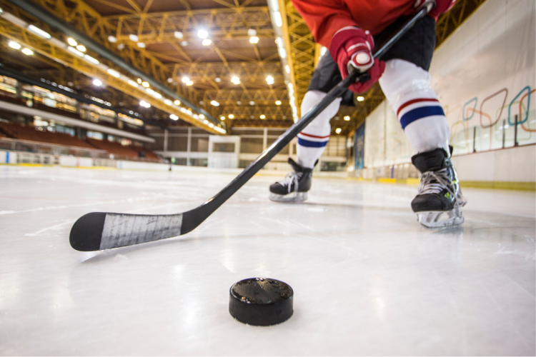 A hockey player skating with the puck on an indoor rink