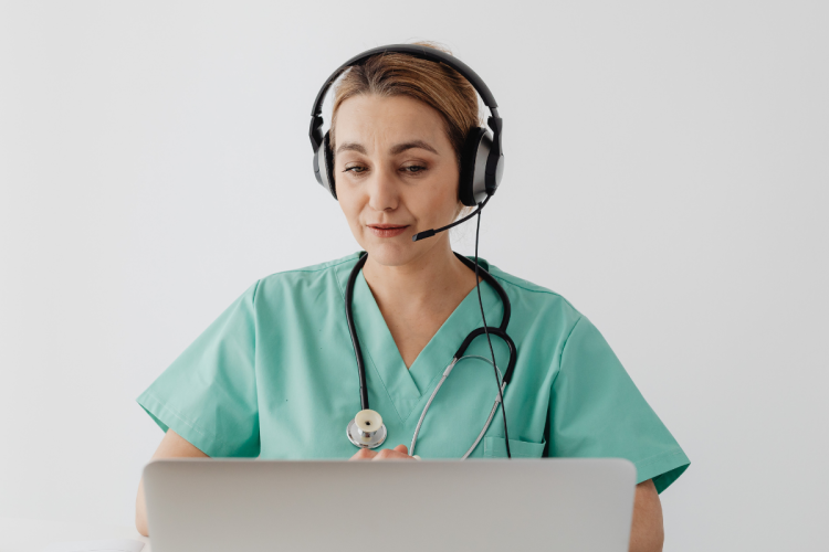 A doctor with a headset on participating in a video call on a laptop