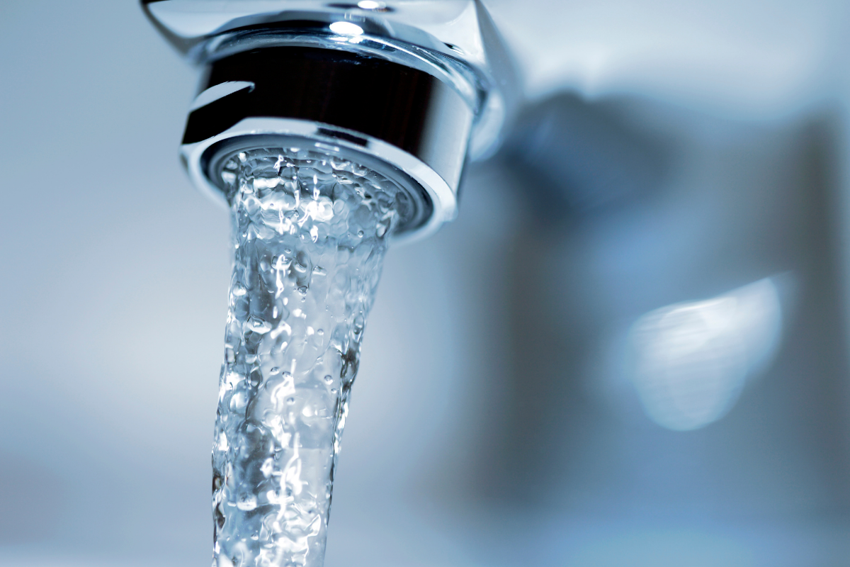 A close up photo of a running bathroom faucet