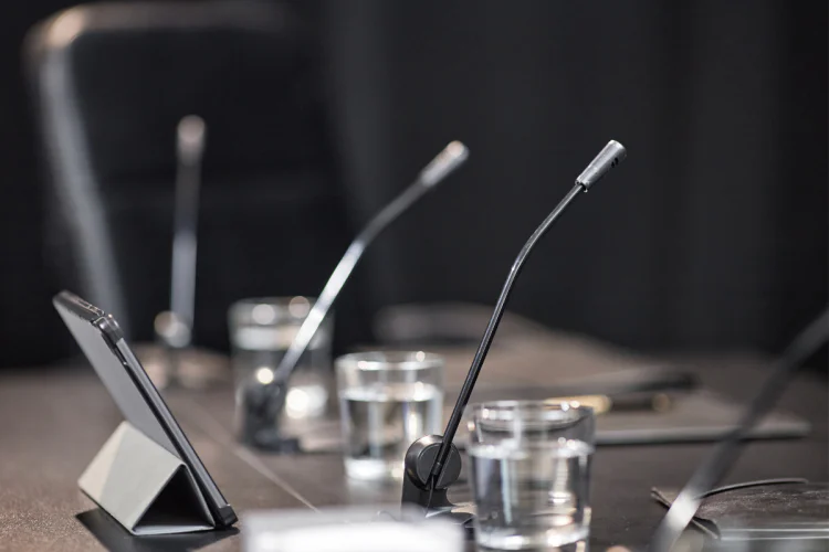 A close up of an empty council desk with microphones and glasses of water