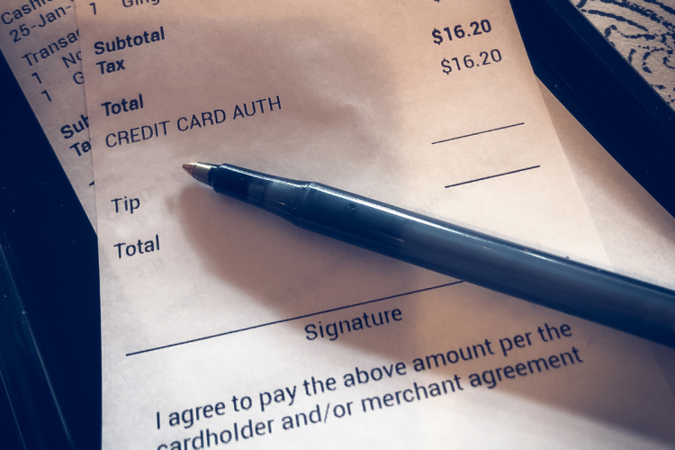 A restaurant bill with a pen pointed at the tip field