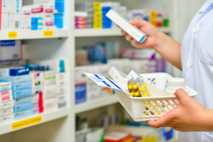 A pharmacist stocking the shelves with a basket of medication