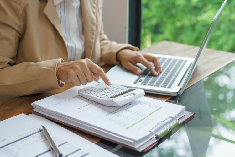 A woman using a laptop and calculator to do her taxes