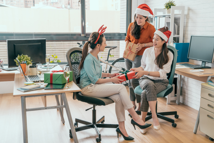 Group of female workers in an office, exchanging holiday gifts