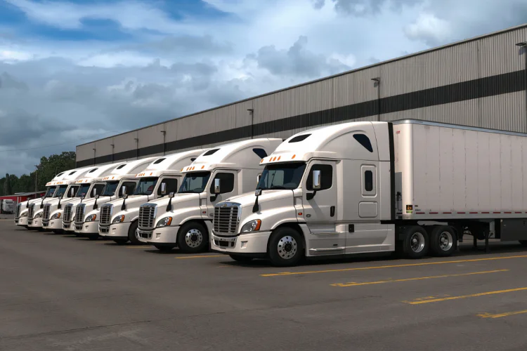 A fleet of semi trucks parked in a line near a warehouse