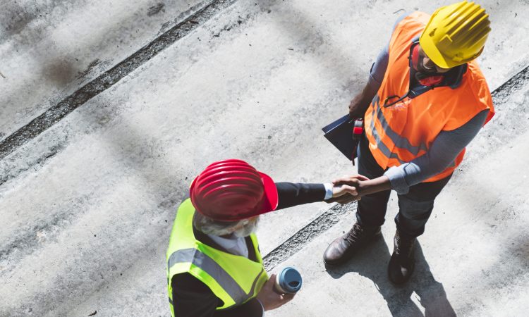 Workers in hard hats and hi-vis vests shake hands