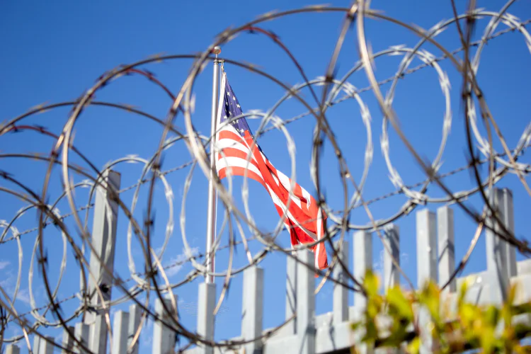 United States flag behind barbed wire fencing