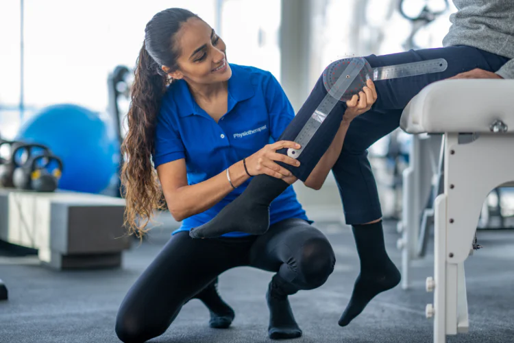 Female physiotherapist measures patient's range of motion