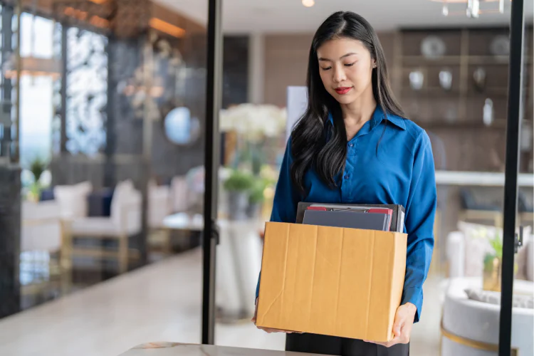 A woman who has just been fired carrying her things out of her workplace in a box
