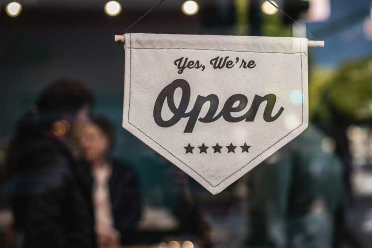 A sign reading "Yes, we're open" on the window of a busy restaurant