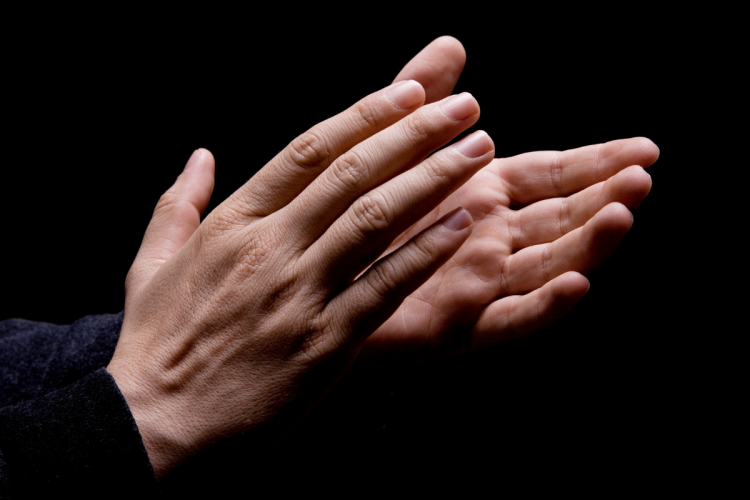 Hands clapping in front of a black background