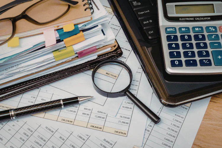 Financial papers, magnifying glass, calculator and glasses