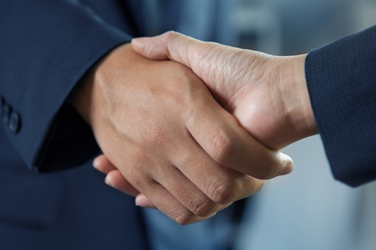 A close-up of two people in suits shaking hands