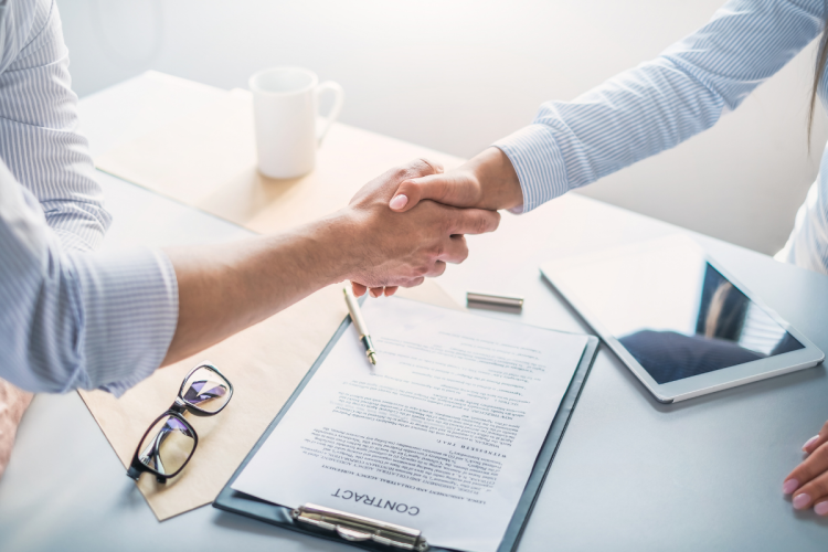 Two hands shaking over an employment contract