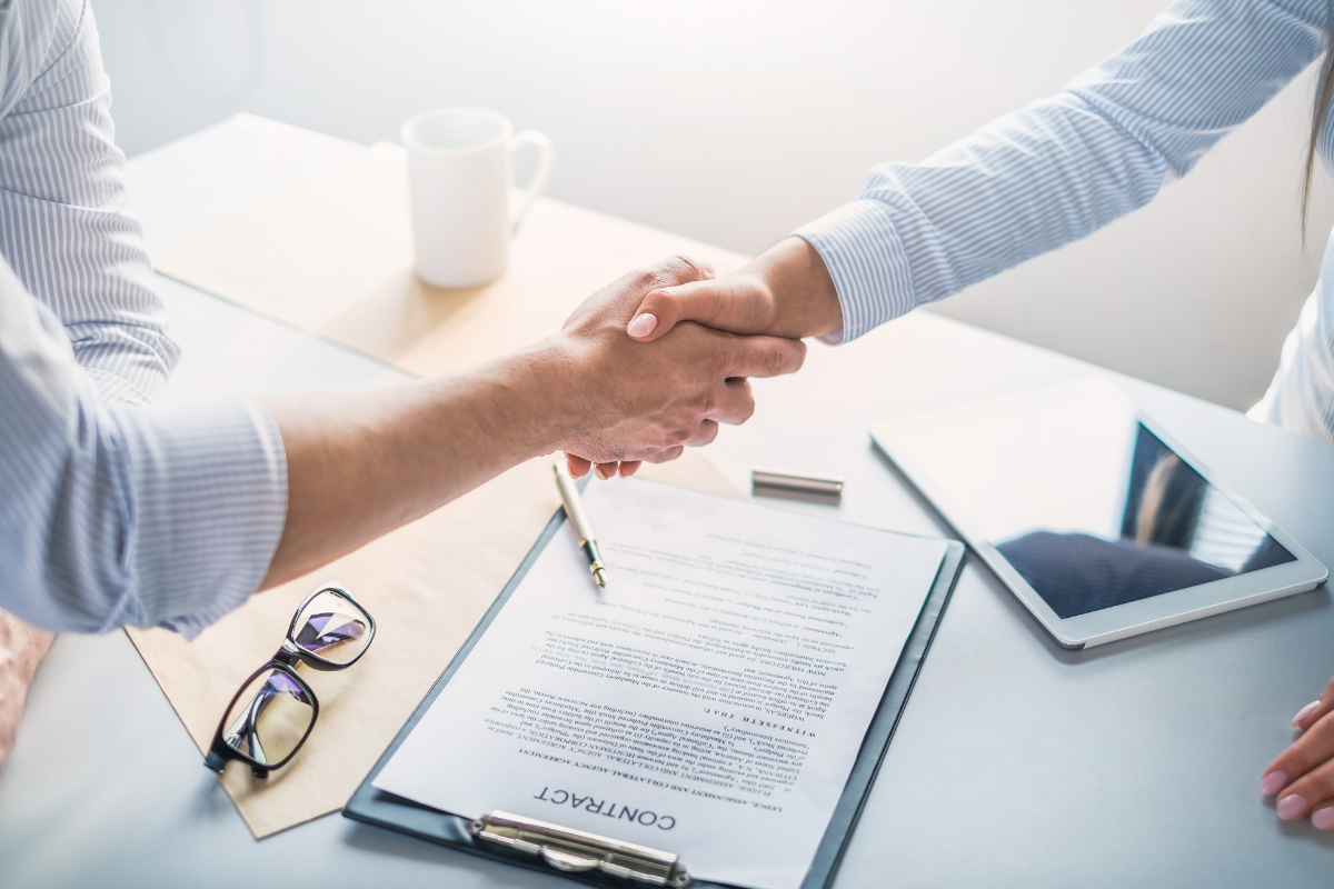 Two hands shaking over an employment contract