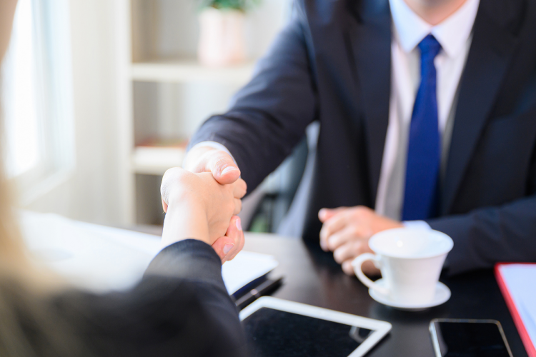 Two businesspeople shaking hands over a desk