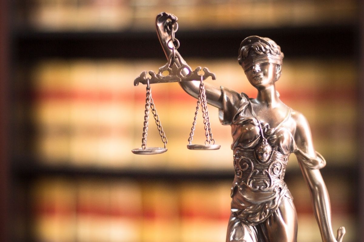 A statue of Lady Justice against a background bookshelf