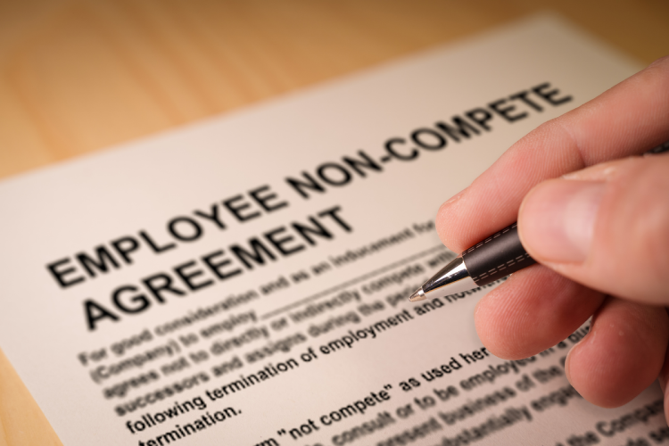 A closeup of someone signing an employee non-compete agreement
