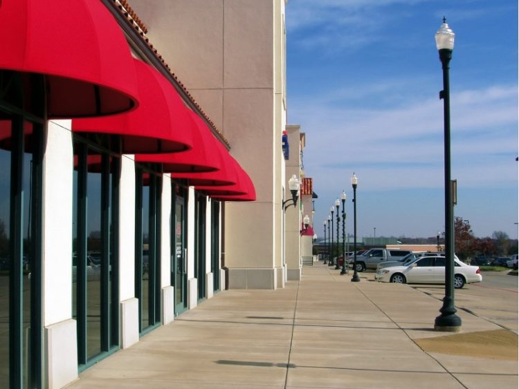 Sidewalk in front of strip mall with storefronts shown in profile