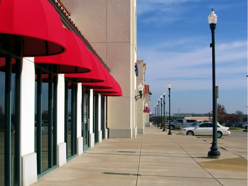 Sidewalk in front of strip mall with storefronts shown in profile