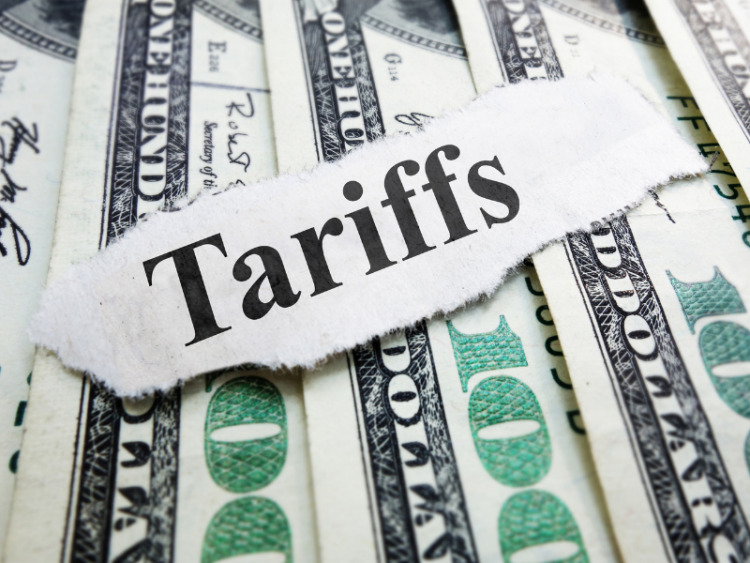 Cut out lettering spelling tariffs on top of a pile of U.S. $100 bills