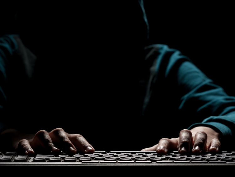 A shadowed figure typing ominously in a dark room