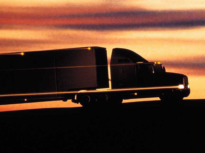 A quickly moving, motion blurred semi truck at sunset