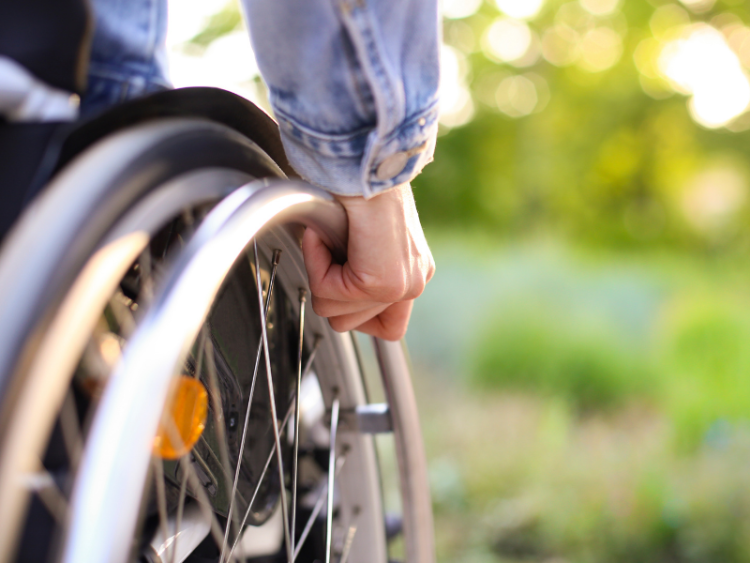 A closeup of a wheelchair user's hand on the wheel of their chair