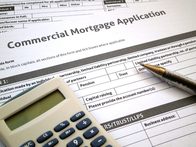 A close up of a commercial mortgage application form with calculator and pen laying on top