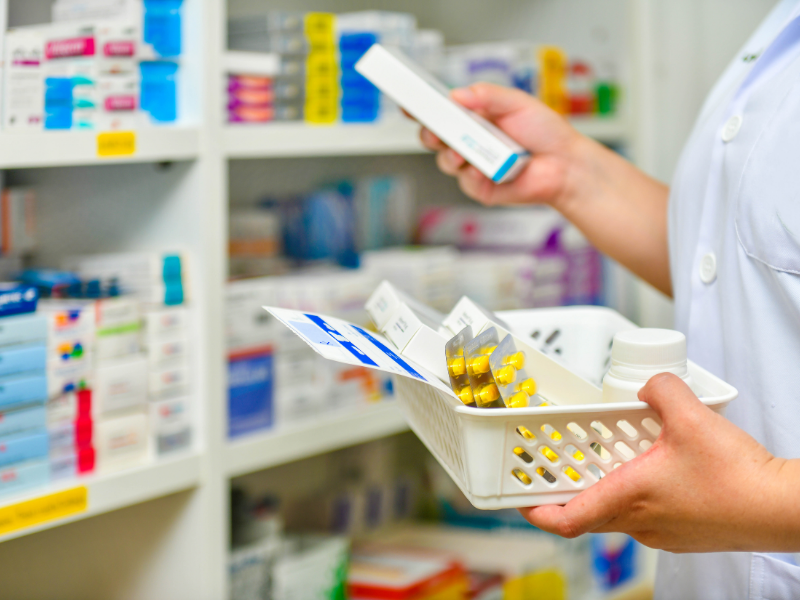 A pharmacist selecting medication from a pharmacy shelf