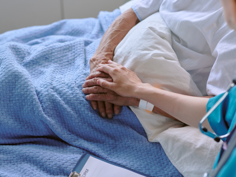 A nurse sitting with an elderly patient in the hospital